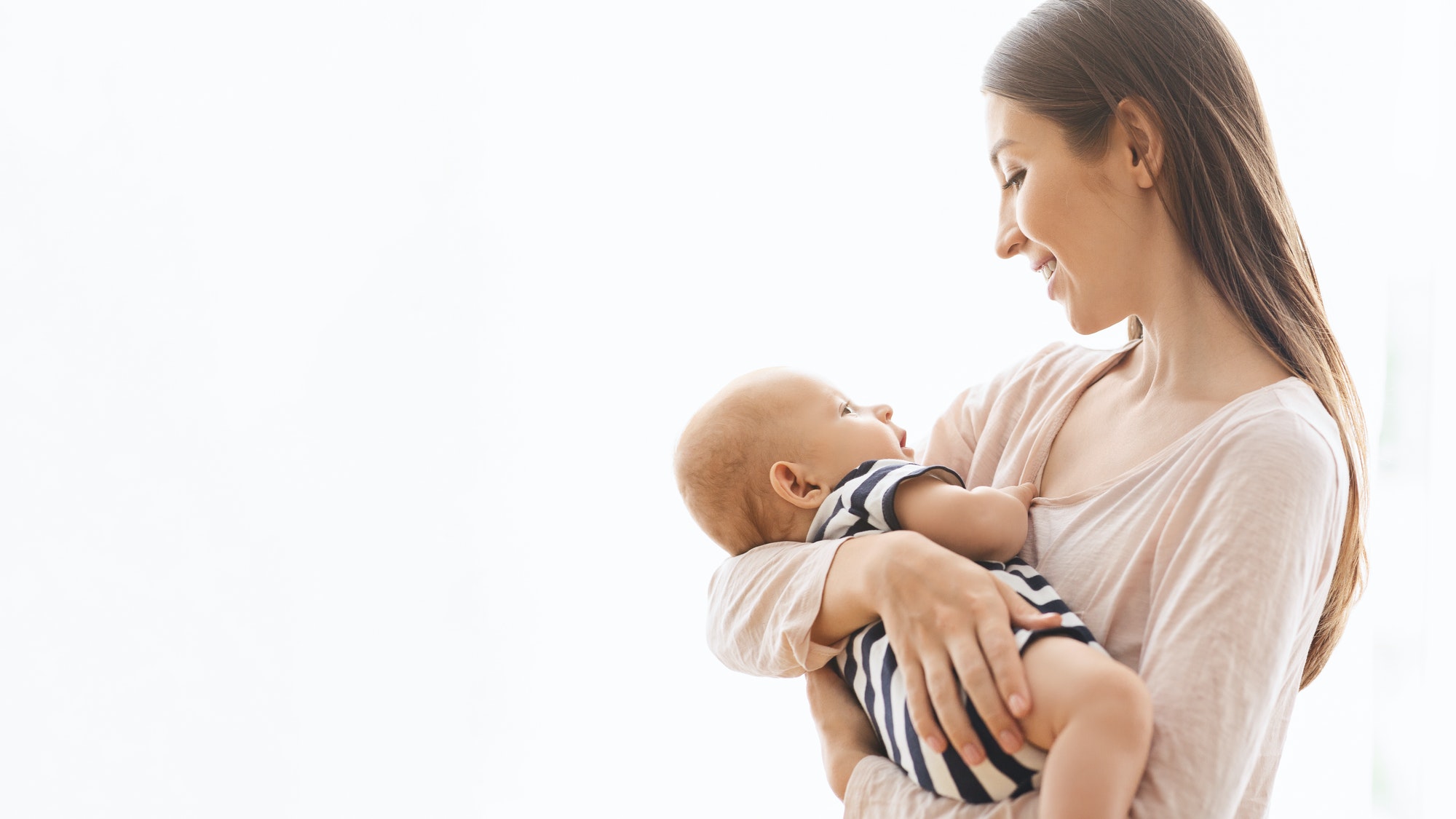 Adorable infant baby in the arms of his mom over white background